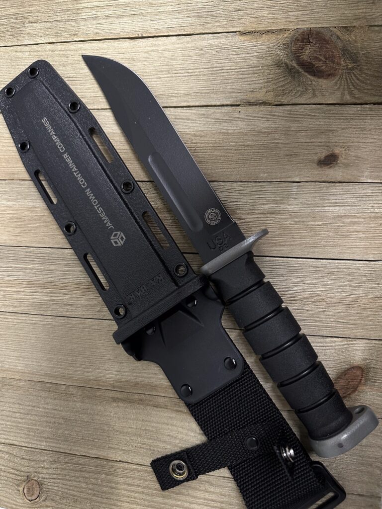 A black KA-BAR knife with its hard sheath, laser-engraved with the "Jamestown Container Companies" logo.