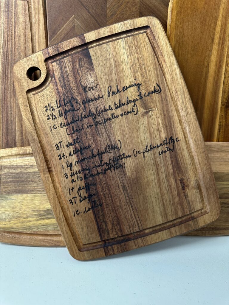 A wooden cutting board laser-engraved with a custom handwritten recipe.