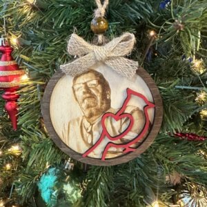 ersonalized Cardinal Memorial Ornament hanging on a Christmas tree featuring a stained wood frame, laser engraved photo portrait, and red cardinal overlay