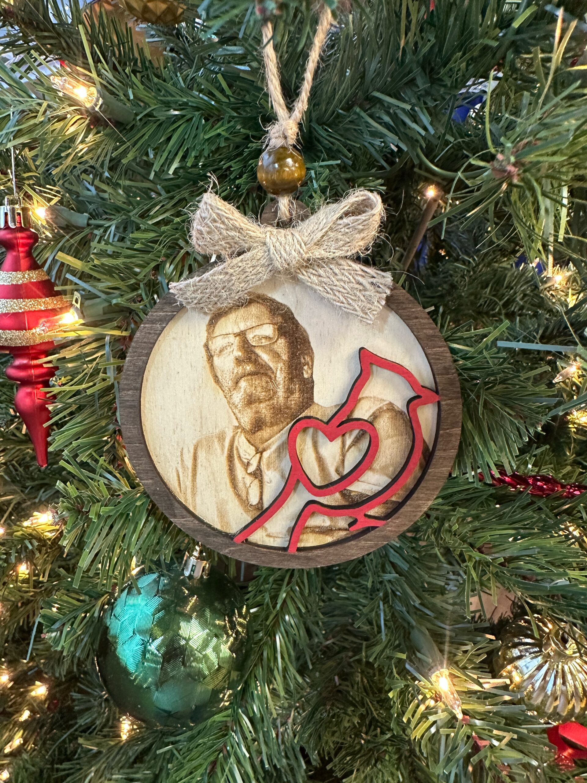 Personalized Cardinal Memorial Ornament – "Angels Are Near" Photo Tribute 1 ersonalized Cardinal Memorial Ornament hanging on a Christmas tree featuring a stained wood frame, laser engraved photo portrait, and red cardinal overlay