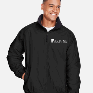 Male model smiling while wearing a custom black Harriton M740 fleece-lined jacket with the 'Artone Furniture by Design' logo on the left chest.